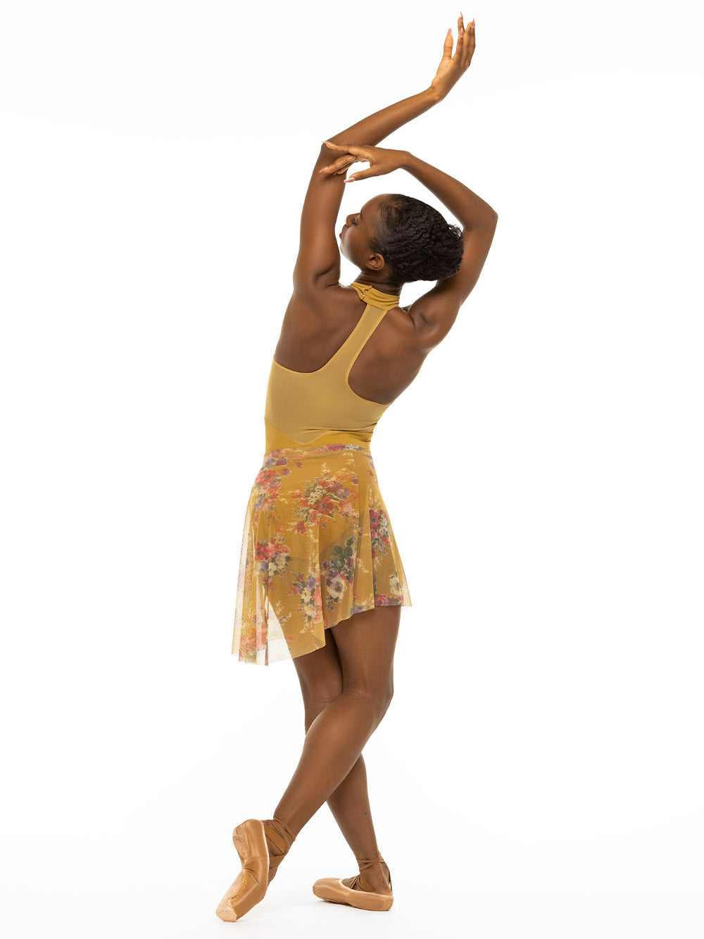 Back of model wearing mustard yellow bodysuit with a collar and mesh racerback with matching yellow floral print skirt.