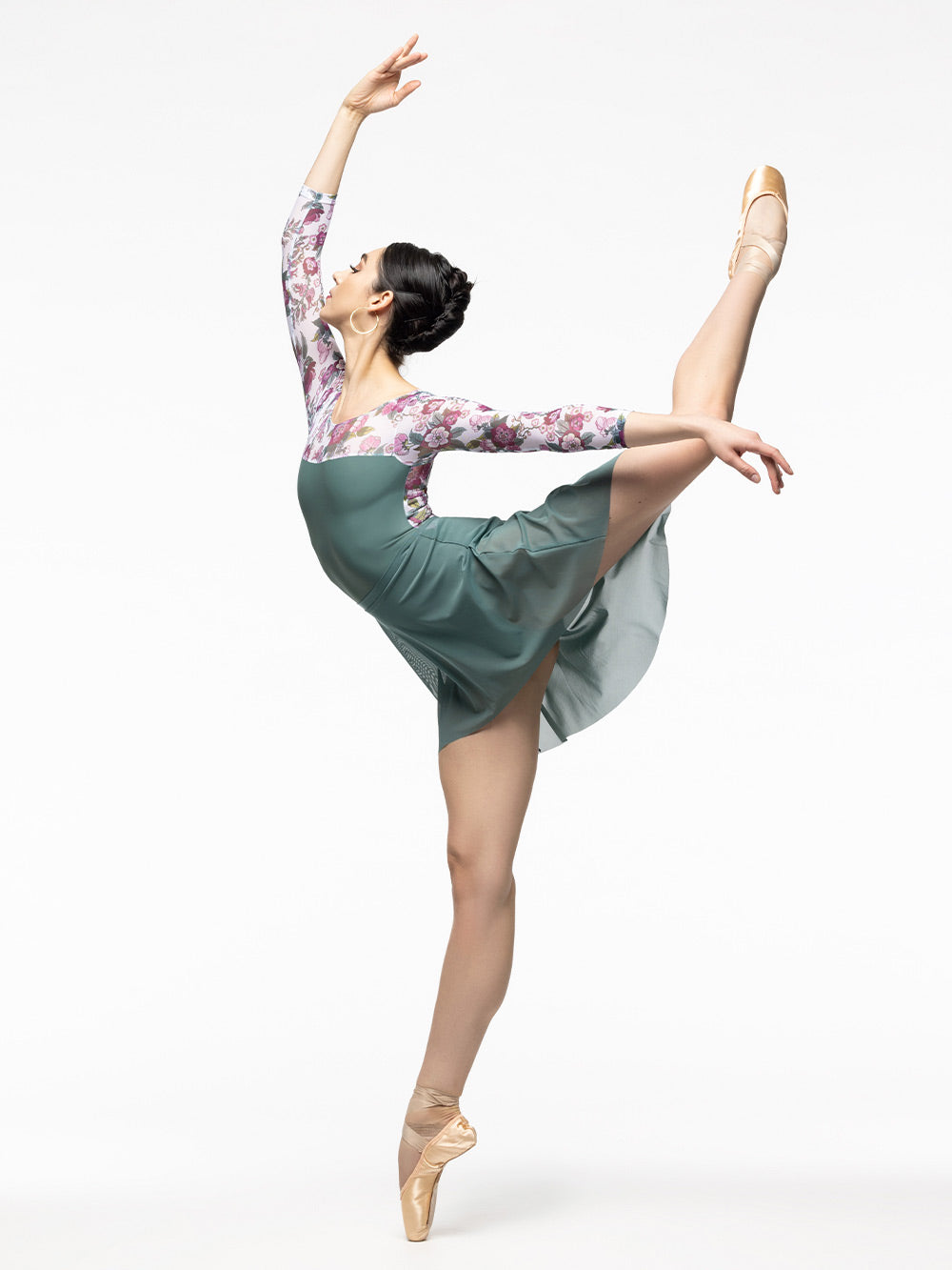Model is wearing pale green leotard with white, magenta, and green floral print mesh top, scoop back, and below elbow sleeves. Paired with pale green high low mesh skirt.