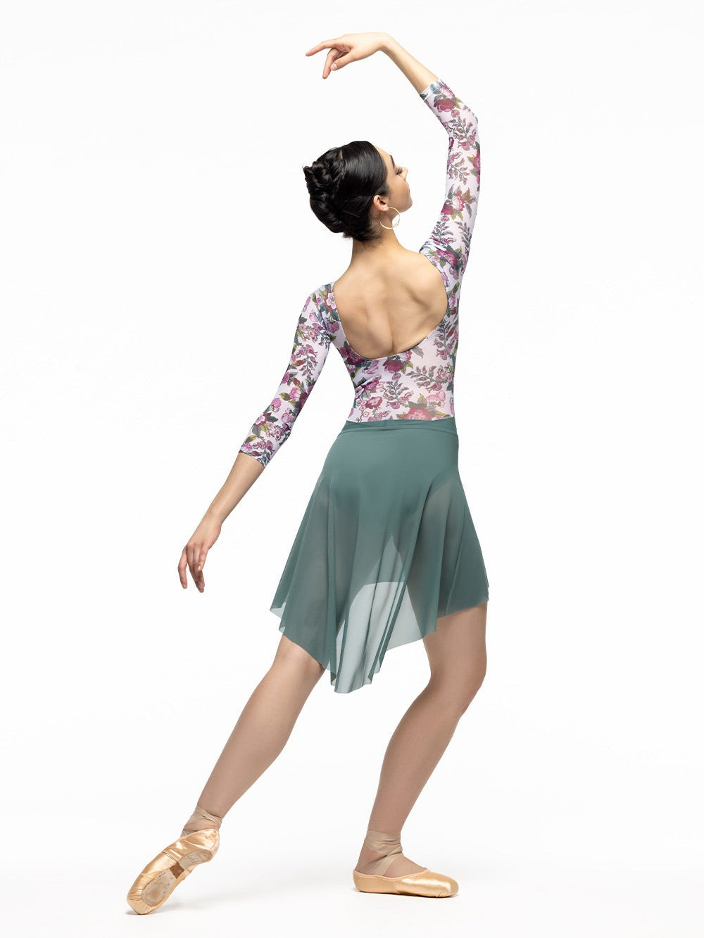 Dancer is facing diagonal back on tendu derriere on plie with front arm on fifth and the other one extended, wearing a Dramatic High-Low Skirt Pale Cacti Mesh RTW.