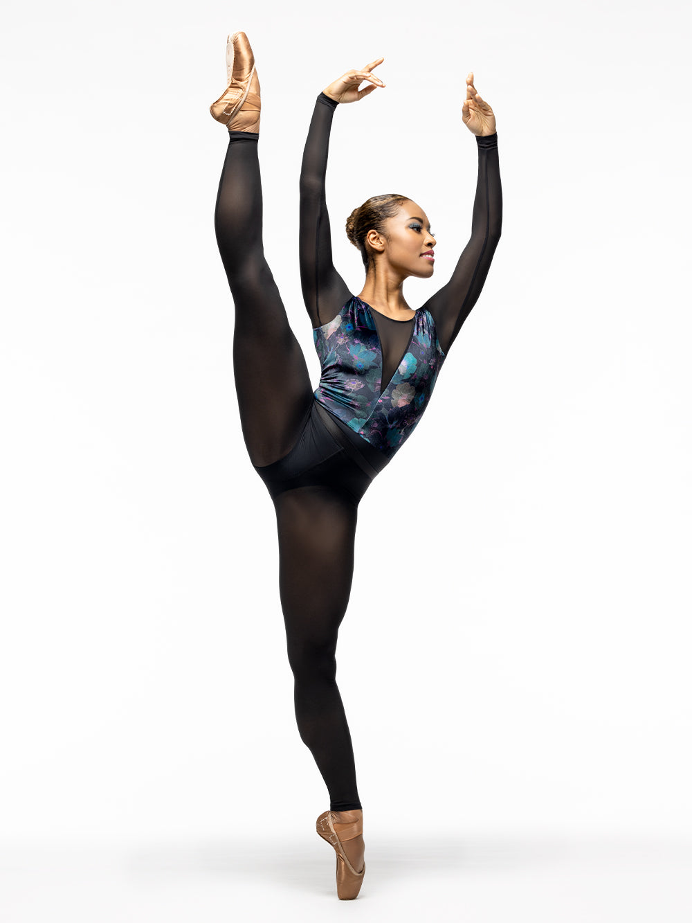 Model is wearing navy, teal, and magenta floral print velvet leotard with black base, black mesh deep v front and back panels, and long sleeves. Paired with black mesh back seam tights.