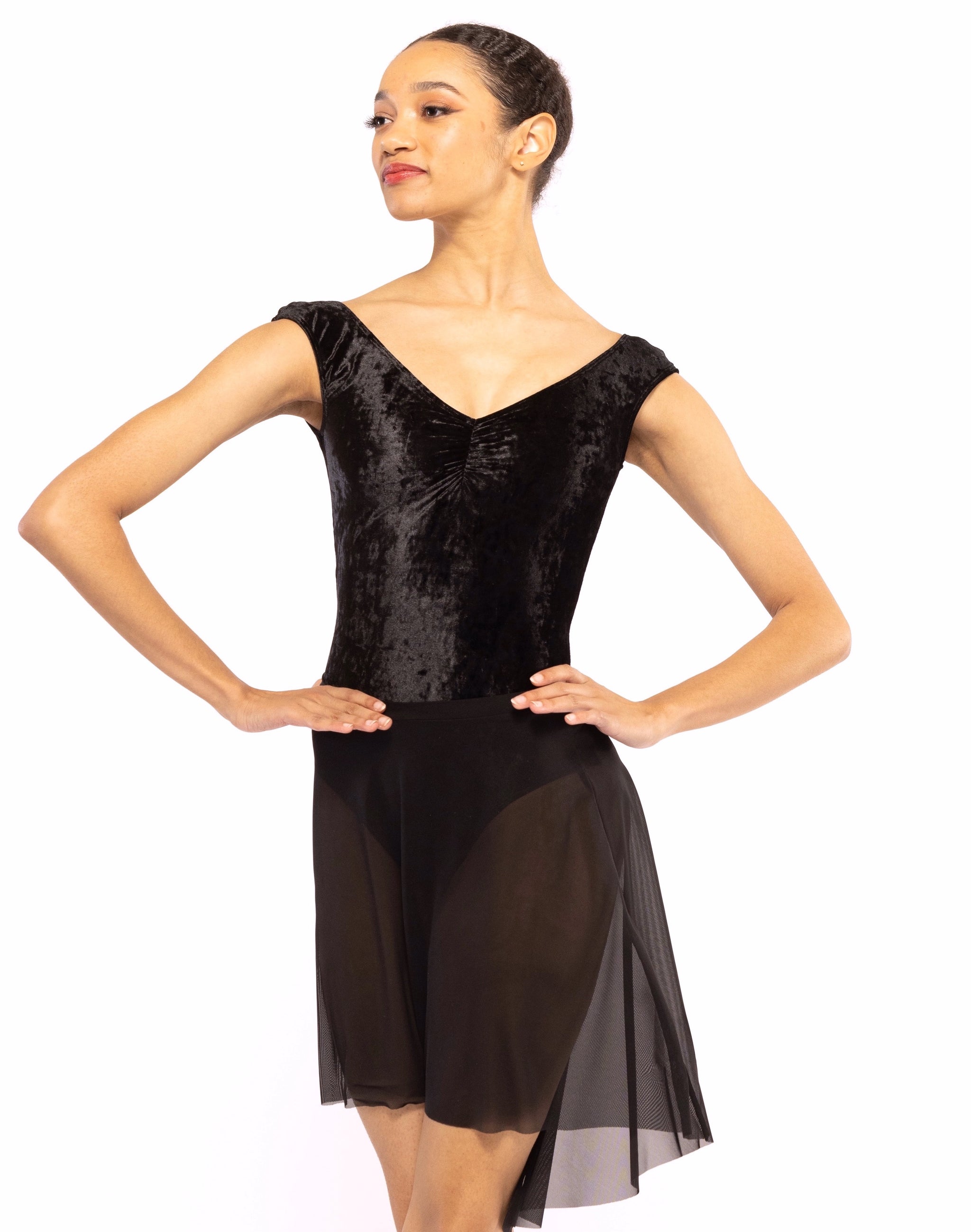 Dancer is facing front with both arms on the hip, wearing a Mid High-Low Skirt Black Mesh RTW.