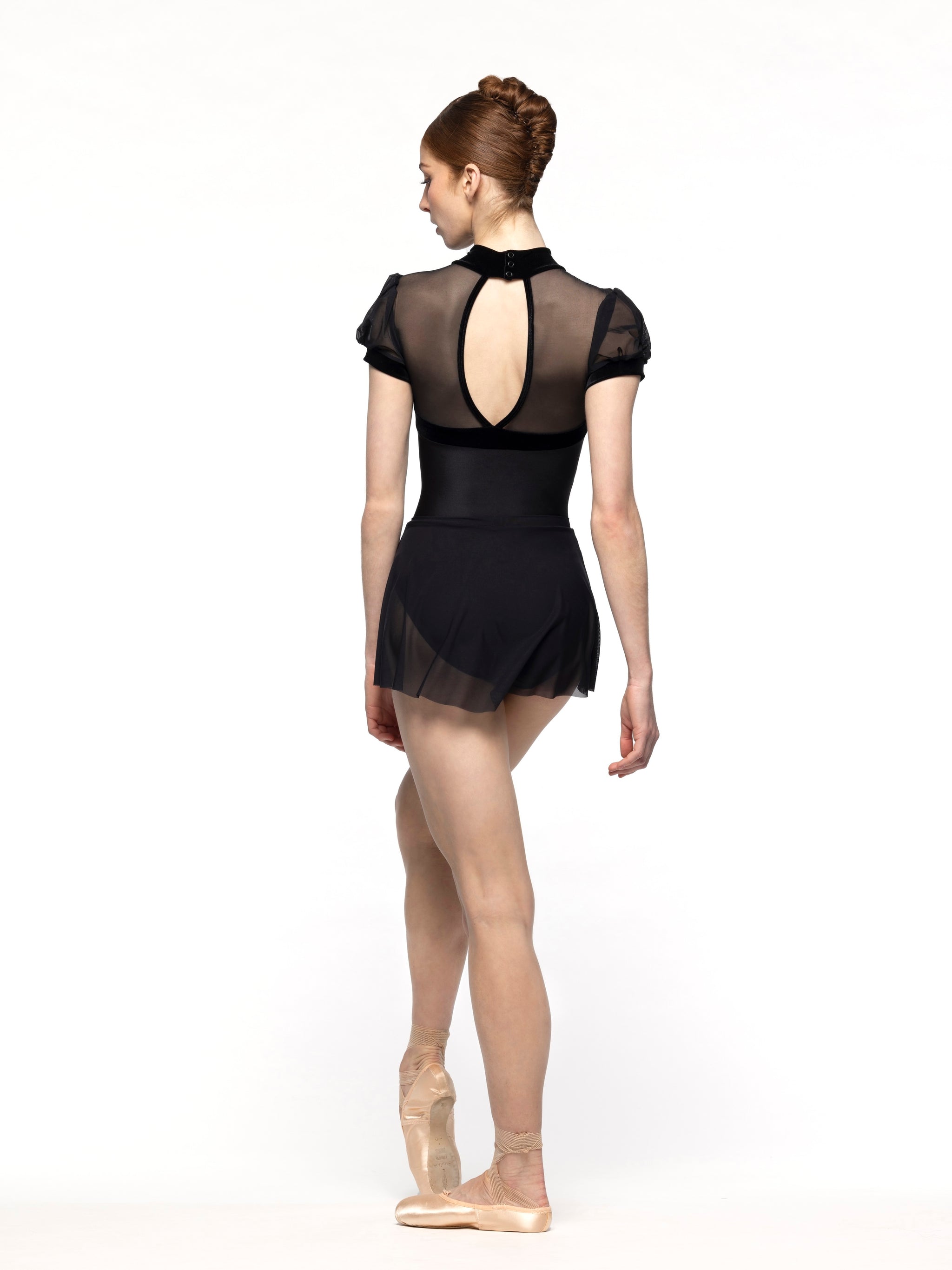 Dancer is facing diagonal back with arms resting and one leg on point crossed close, wearing a Flare Skirt Black Mesh RTW.