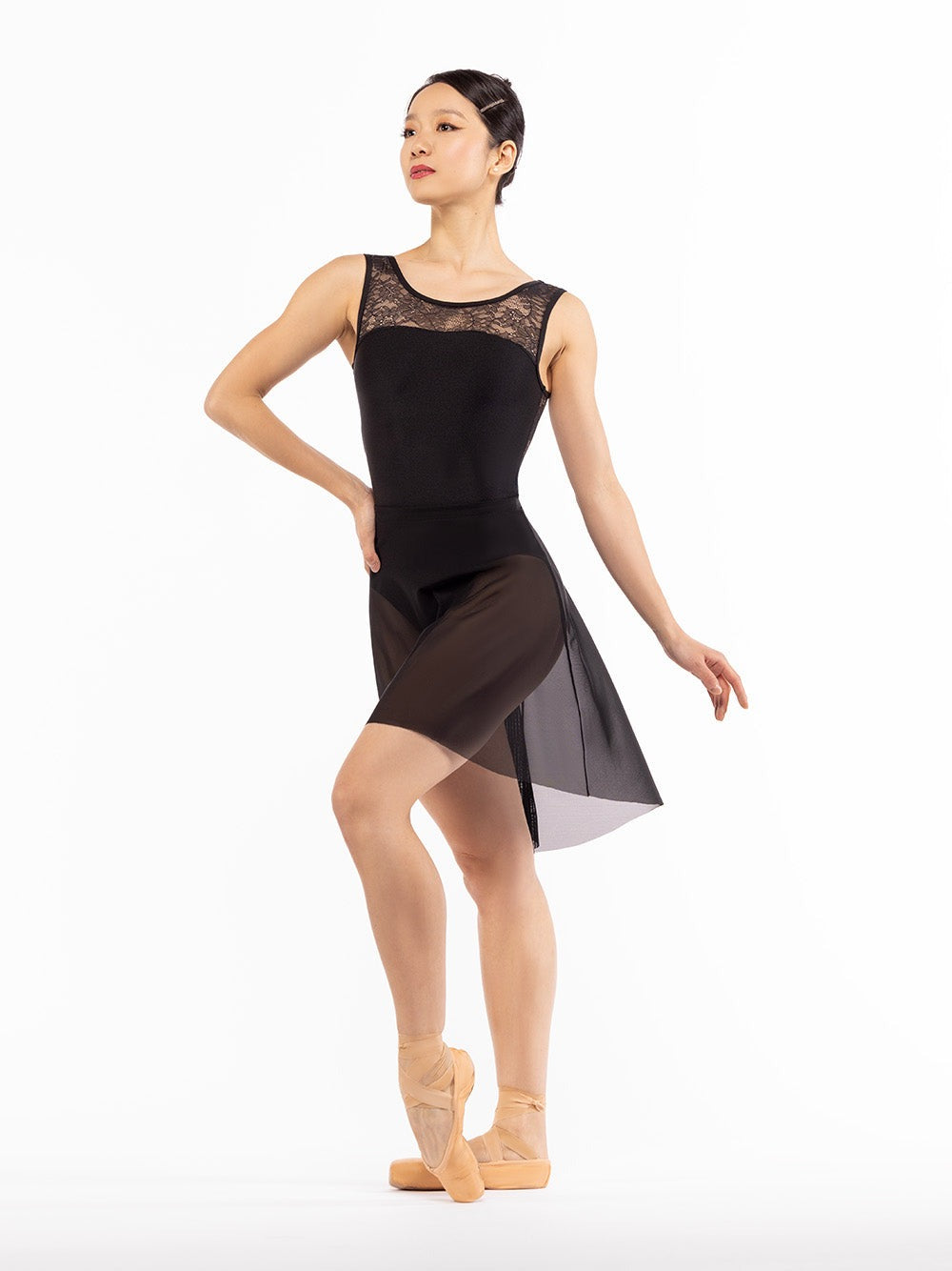 Dancer is facing front with one hand on the hip and one leg on point crossed in front, wearing a Back Tuck Skirt Black Mesh RTW.