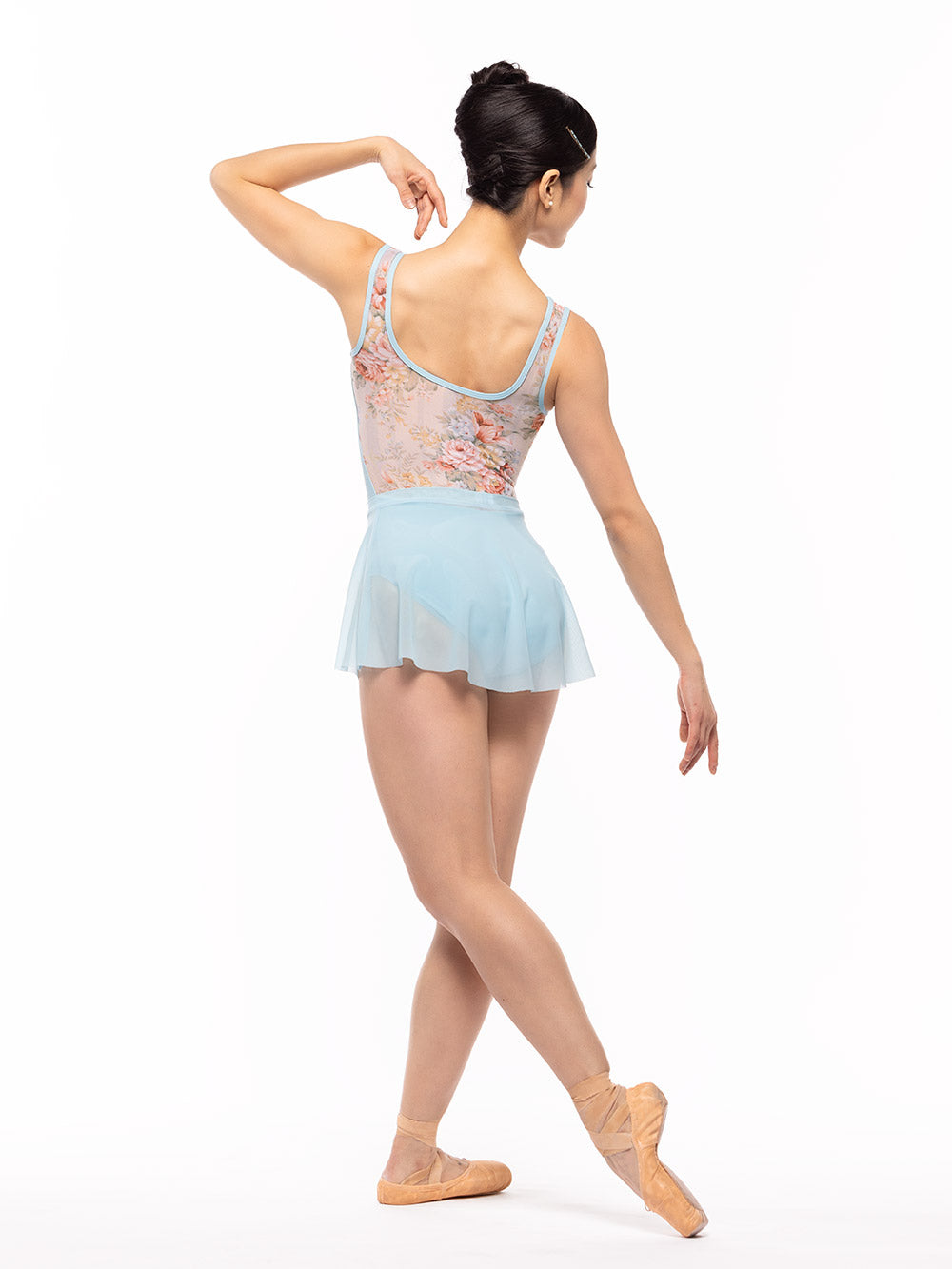 Dancer is facing diagonal back on cou-de-pie flat derriere with one arm on the shoulder, wearing a Flare Skirt Blue Star Mesh RTW.