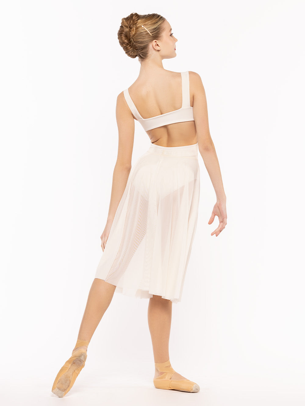 Posing in profile on tendu derriere, dancer is wearing a Circle Skirt Cream Mesh RTW.