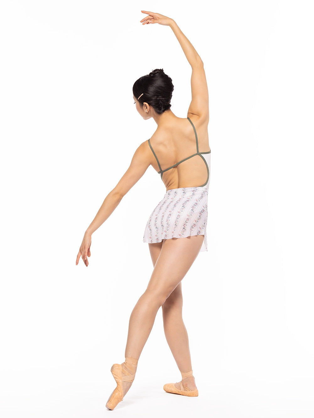 Dancer is facing back on tendu croise derriere with arms on fifth and a la seconde, wearing a Tulip Skirt Delightful Mesh RTW.