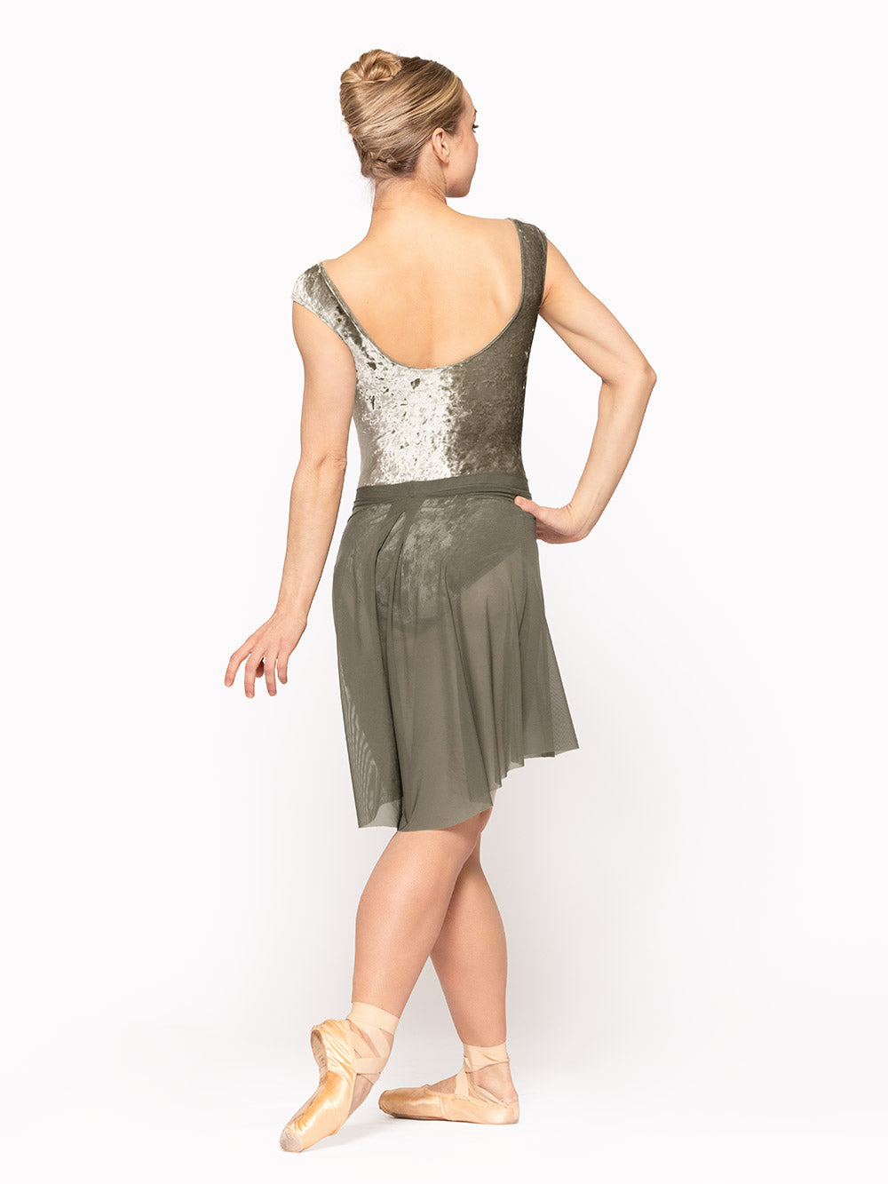 Dancer is facing back on cou-de-pie flat derriere with one arm on the hip, wearing a Back Tuck Skirt Dusty Olive Mesh RTW.