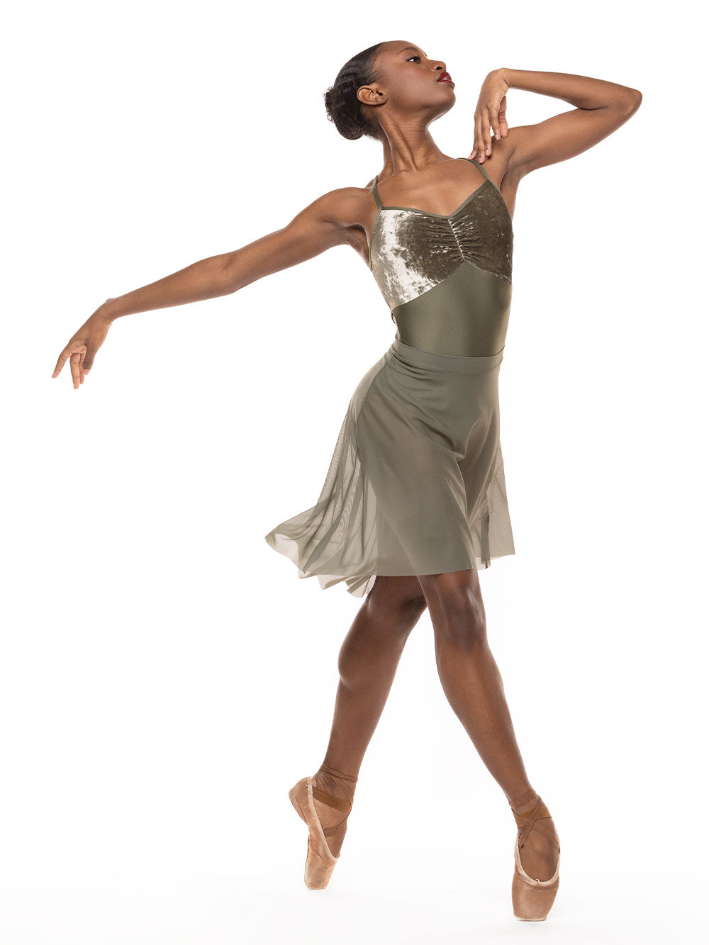 Dancer is profile in four position on point with one arm on the shoulder, wearing a Back Tuck Skirt Dusty Olive Mesh RTW.