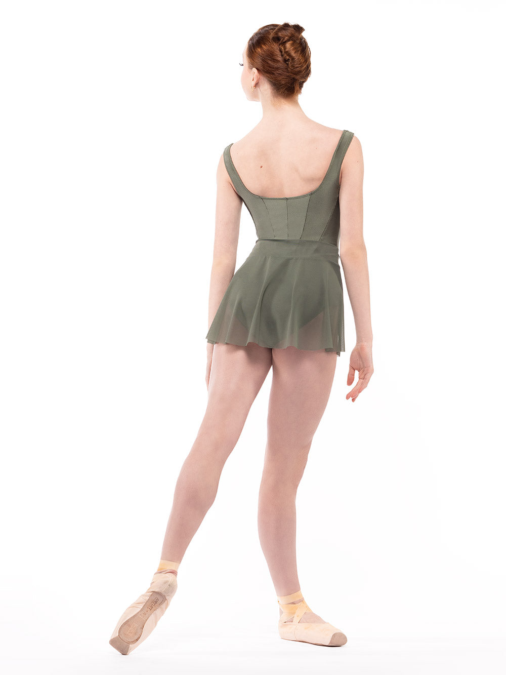 Dancer is facing diagonal back on tendu derriere with arm relaxed down, wearing a Diana Leotard Dusty Olive RTW.
