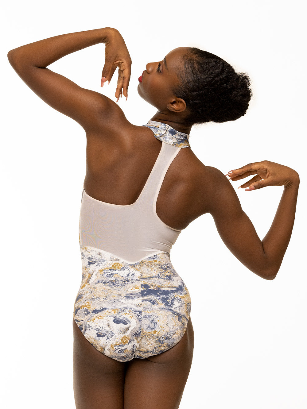 Back of model wearing navy, white, and gold ink swirl print bodysuit with halter neck, deep v mesh panel, and racerback