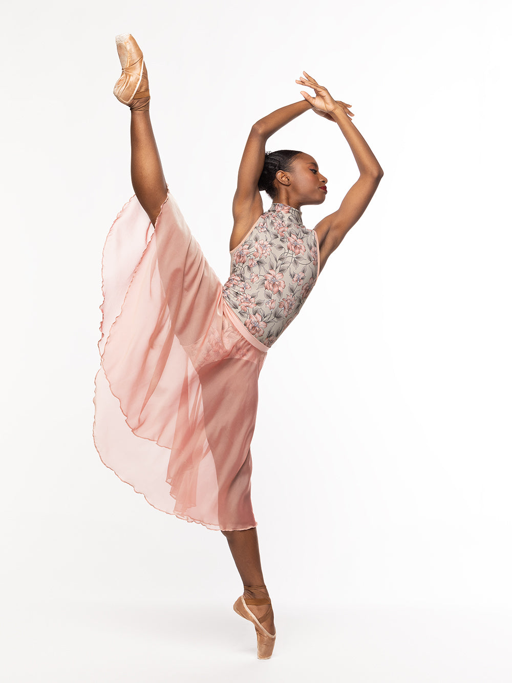 Dancer is facing front on a la seconde high leg on point with both arms crossed on fifth position, wearing a Chiffon Rehearsal Skirt Sandstone RTW.