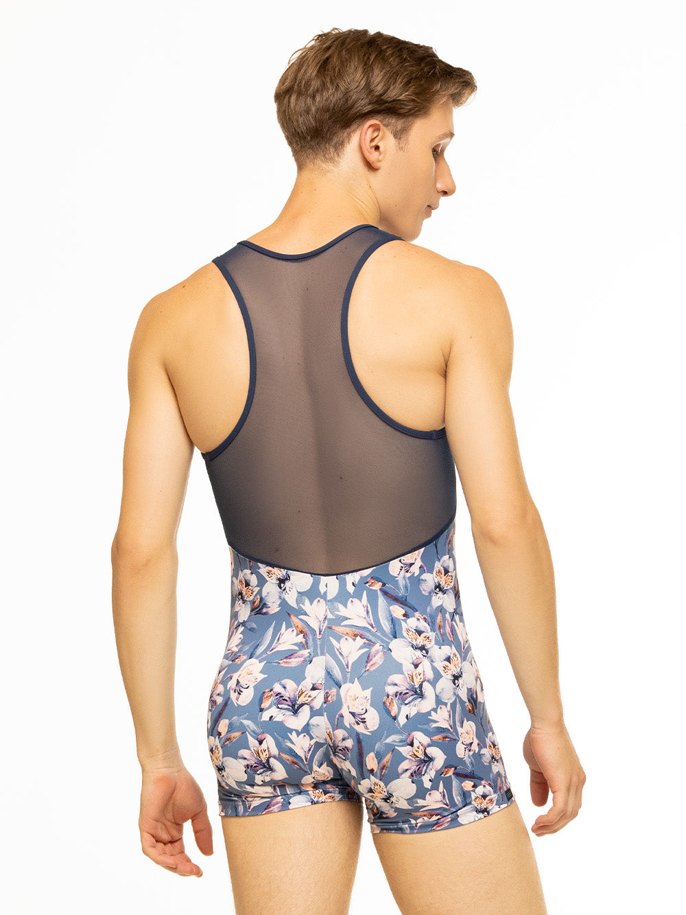 Back of model wearing blue floral print men's activewear onesie with zipper front and navy blue mesh back.