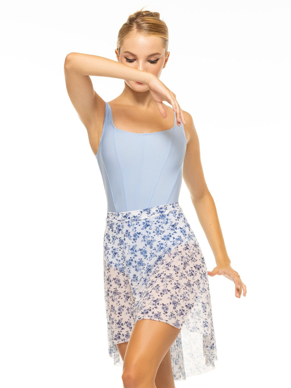Model is wearing shiny blue tank style bodysuit with corset seams paired with a white and blue floral print mesh skirt.