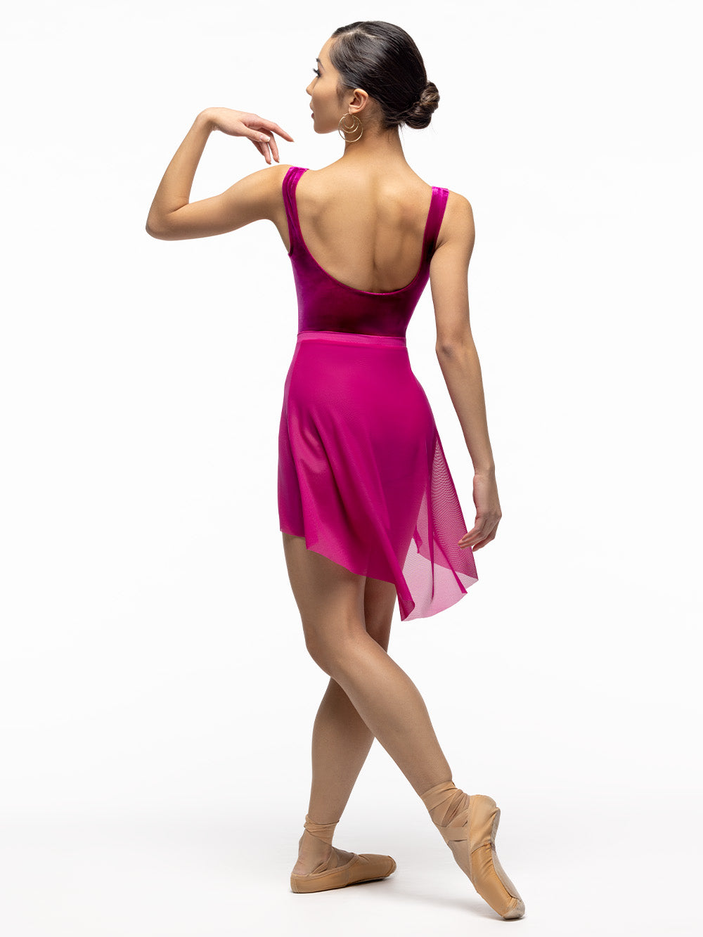 Back of model wearing magenta high low mesh skirt with shiny and velvet magenta leotard.