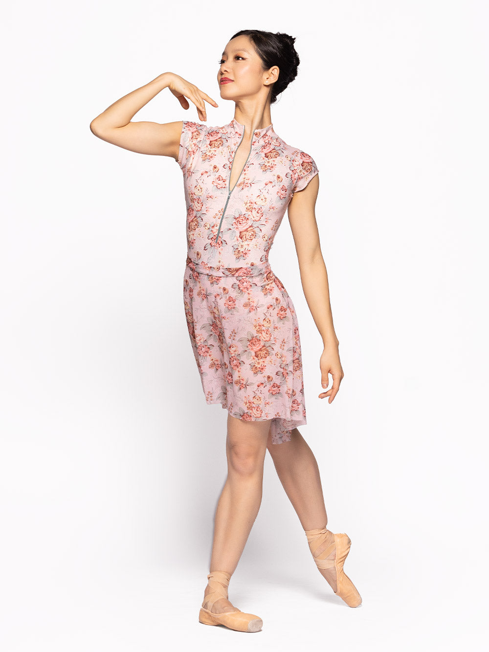 Dancer is facing diagonal front on tendu derriere with arms on fifth position, wearing a Molly Leotard Love Letter RTW.