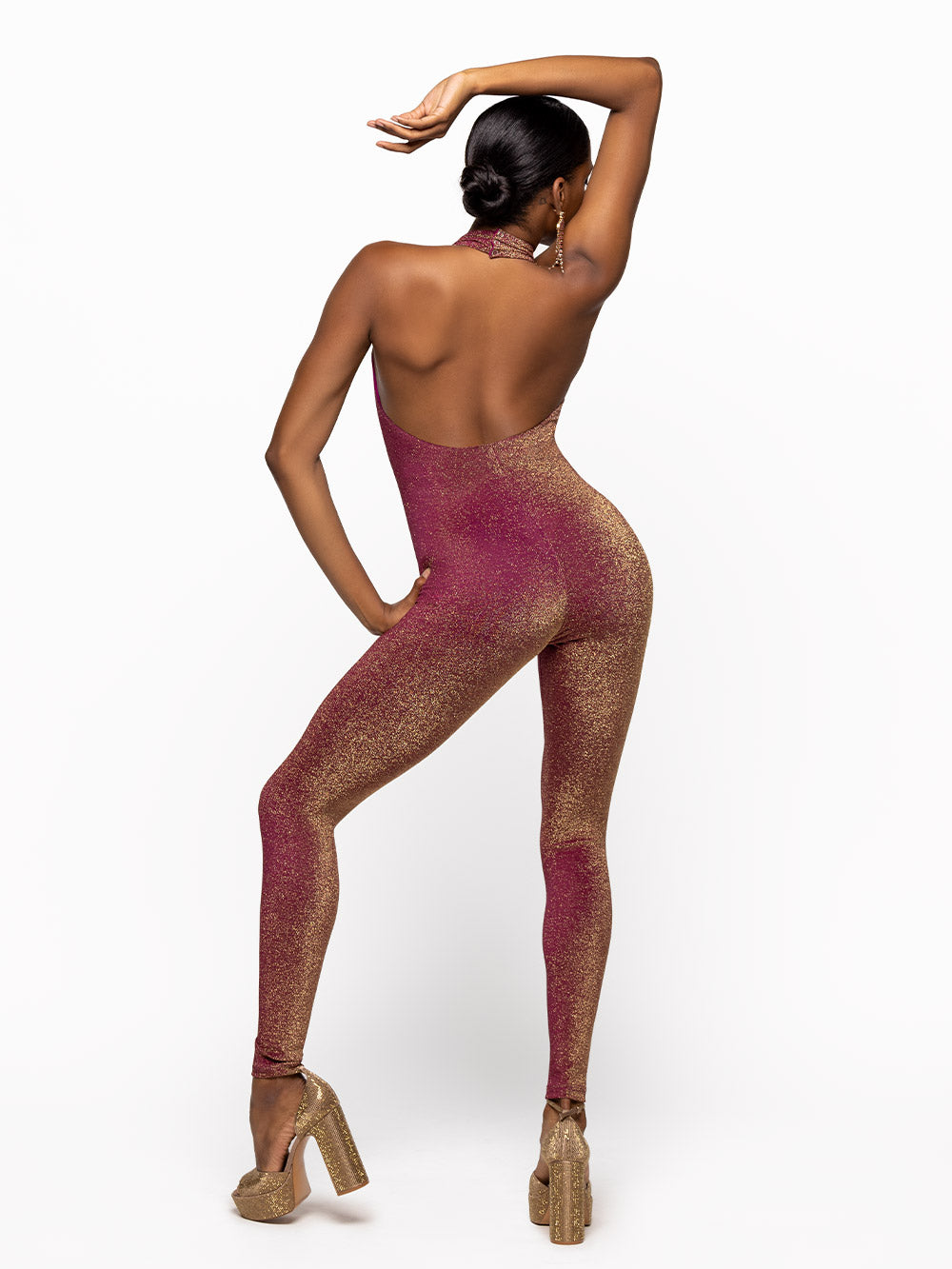 Model is wearing is wearing fuscia onsie with opened back and a collar.