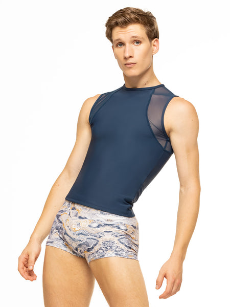 Model is wearing navy blue men's sleeveless top with mesh detail and blue, gold, and white ink swirl print activewear shorts.