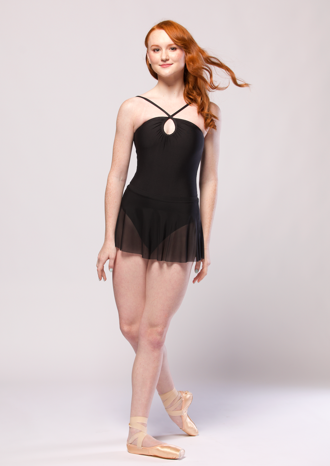 Dancer is facing from on cou-de-pie flat derriere with arms down, wearing a