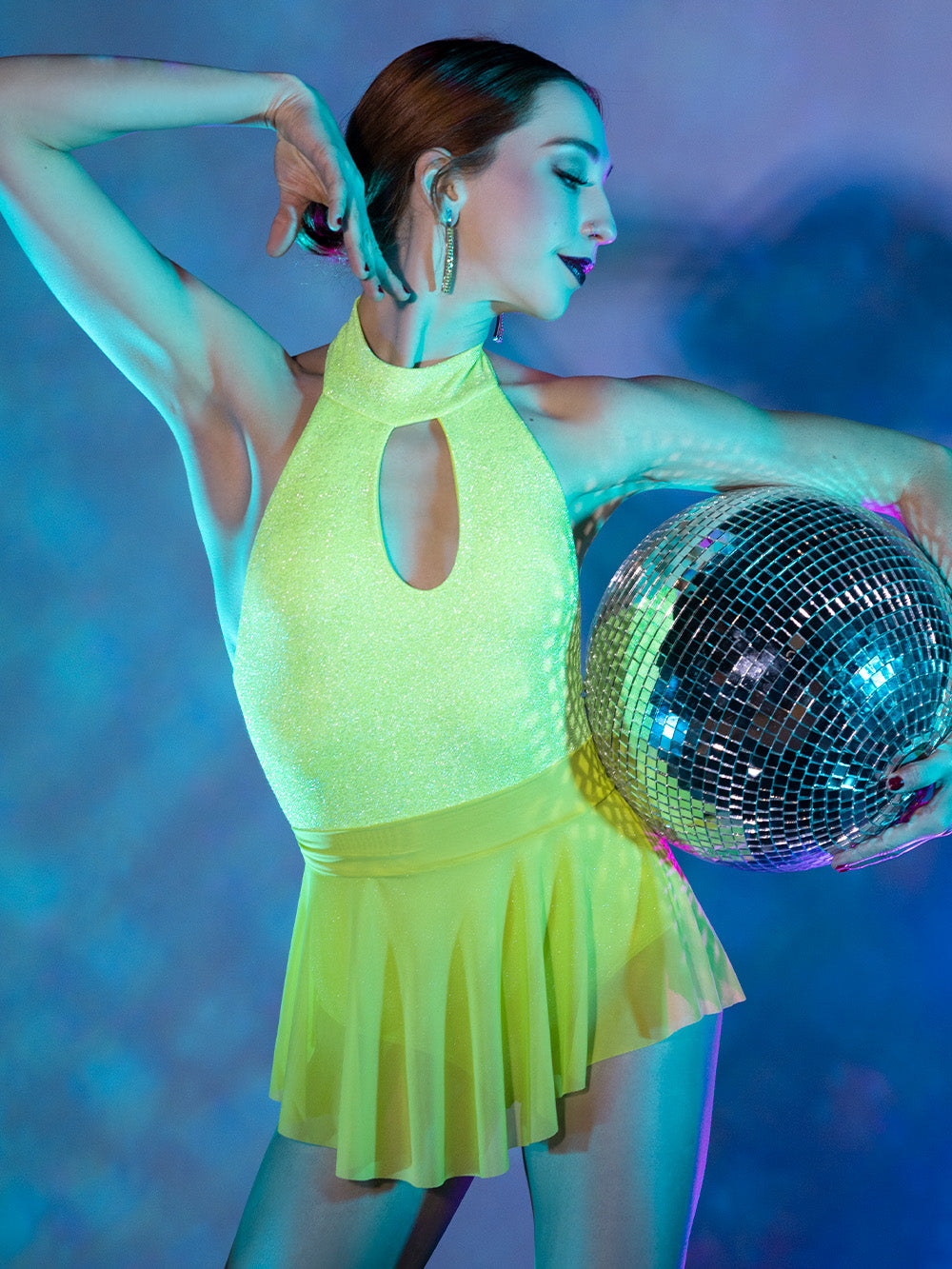 Model is wearing sparkling lime green onsie with opened back and a collar. Paired with short lime green mesh skirt.