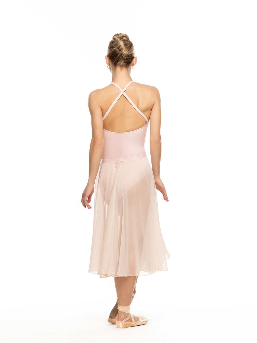 Dancer is facing back with arms relaxed down and one leg crossed in front on point, wearing a Chiffon Rehearsal Skirt Powder Pink RTW.