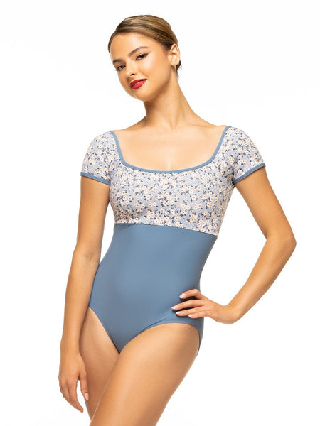 Model is wearing denim blue bodysuit with baby blue floral print top, square neck, and cap sleeves.