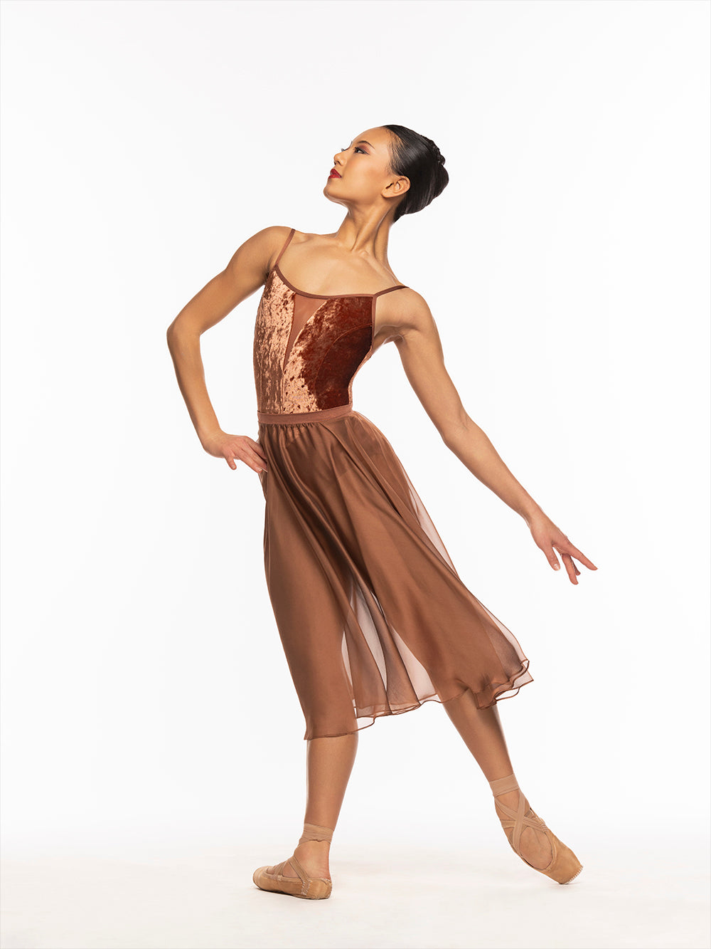 Dancer is profile on tendu derriere with one hand on the hip, wearing a Chiffon Rehearsal Skirt Spice RTW.