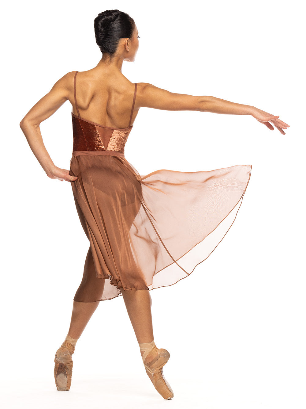Dancer is facing diagonal back on four point position with one hand on the hip and opposite arm extended back and is wearing a Chiffon Rehearsal Skirt Spice RTW.