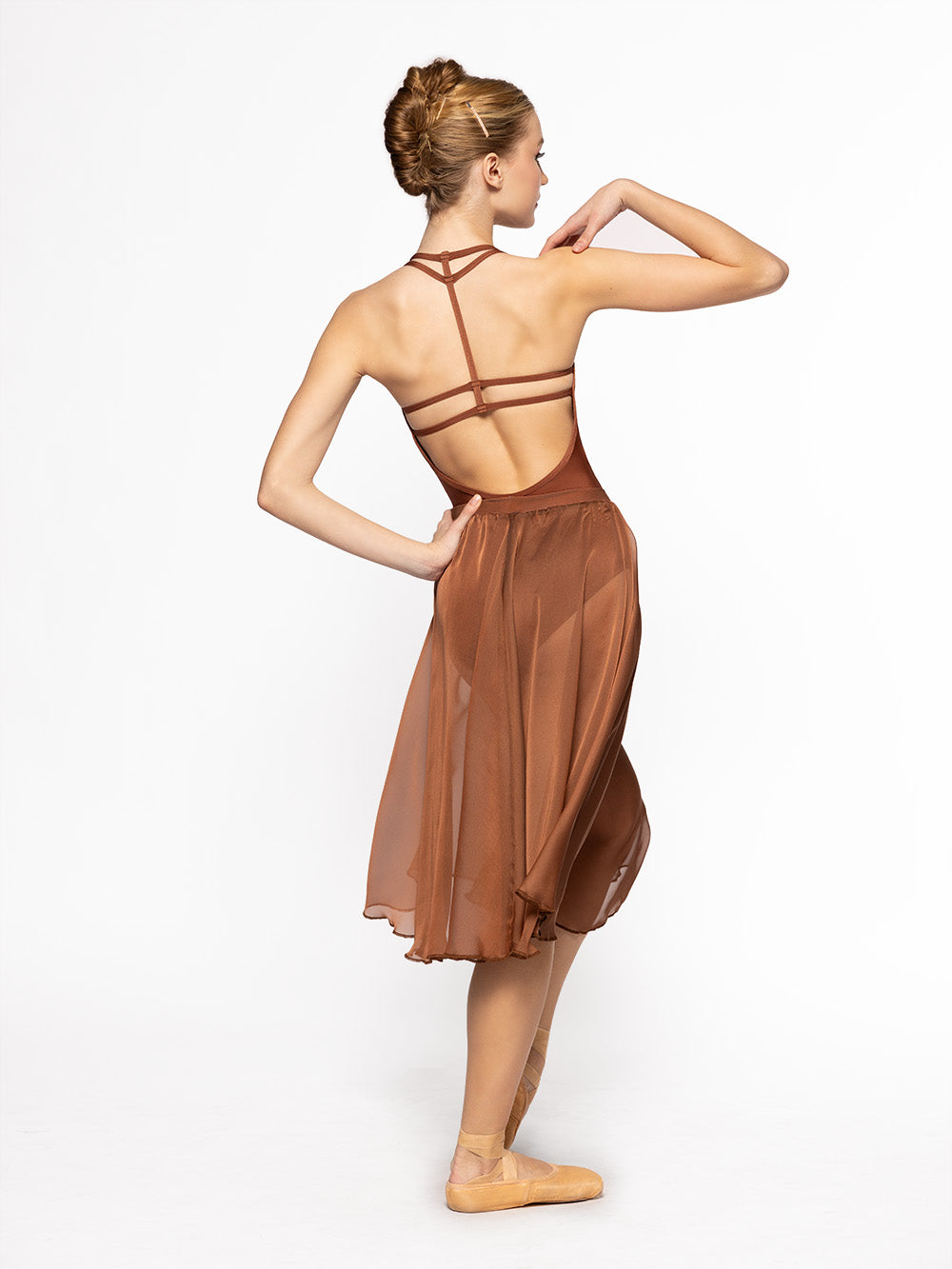 Dancer is facing back with one leg resting on point and one arm on the shoulder while the other is on the hip, and is wearing a Chiffon Rehearsal Skirt Spice RTW.