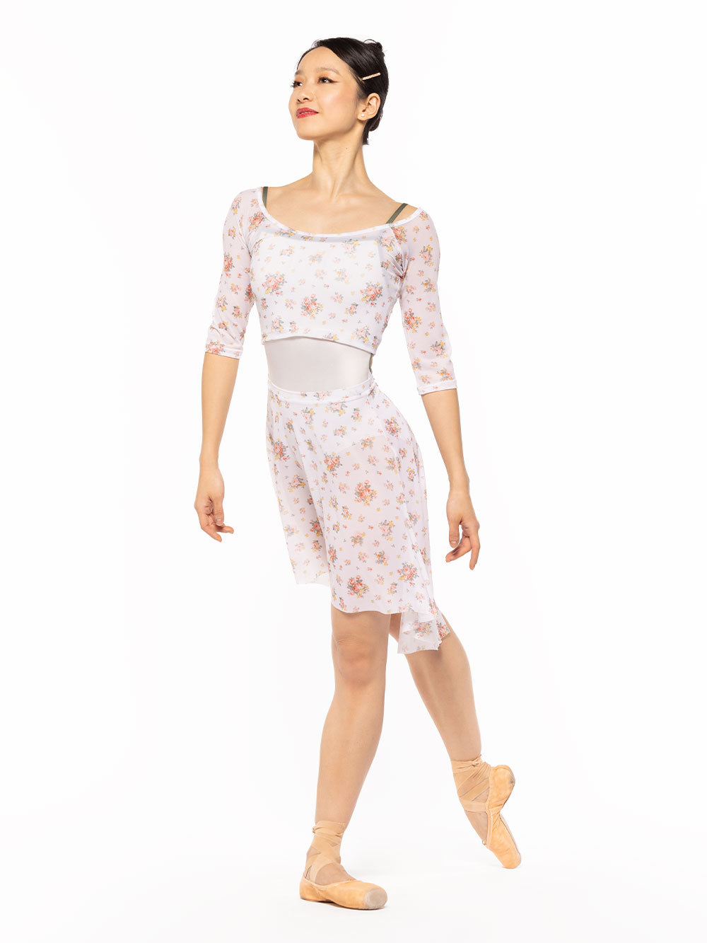 Dancer is facing diagonal front on tendu croise derriere and arms relaxed down, wearing a Candy Leotard Cream RTW.