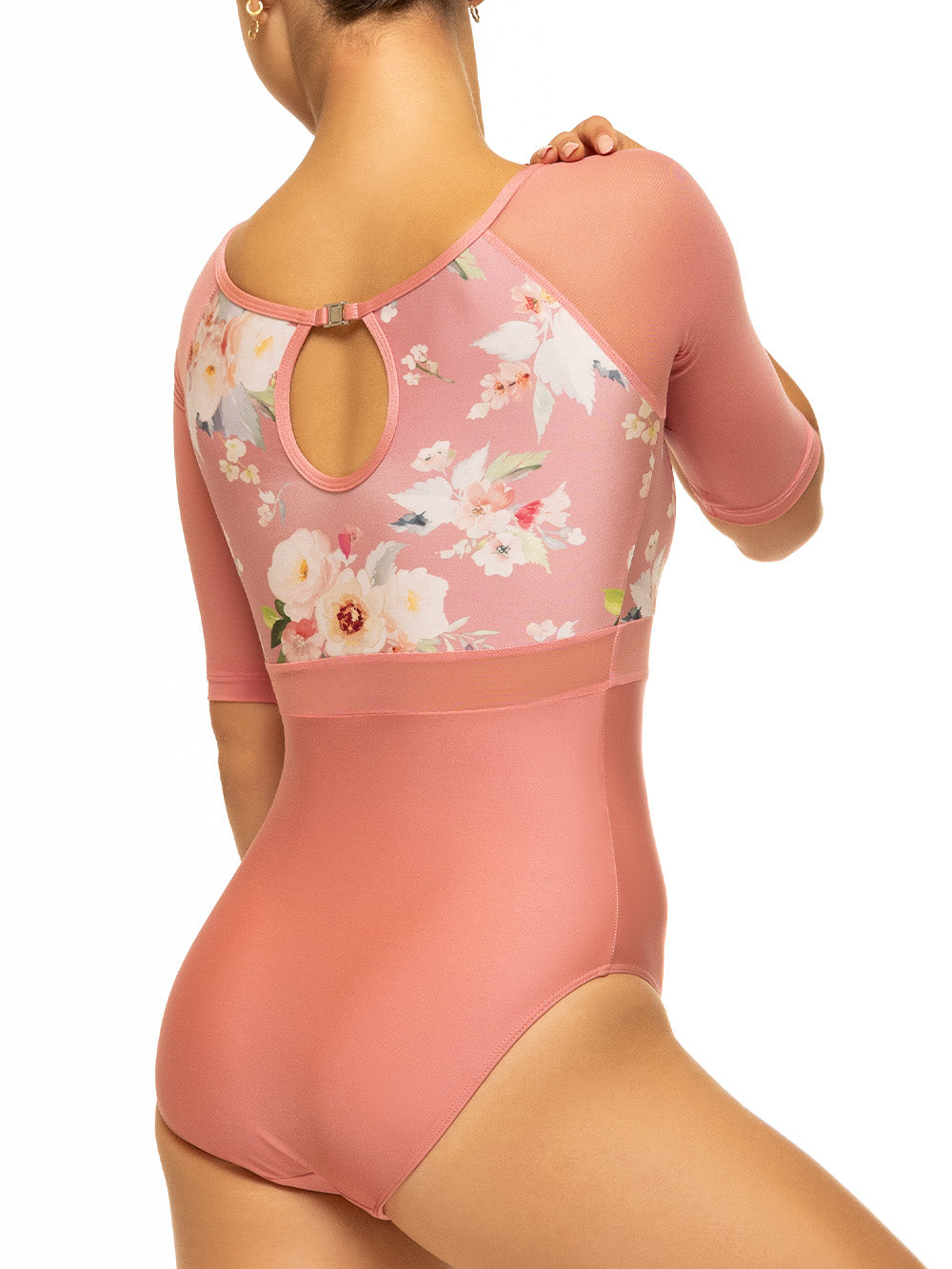 Back of model wearing shiny pink bodysuit with floral print top, mesh middle and sleeves, and back keyhole detail.