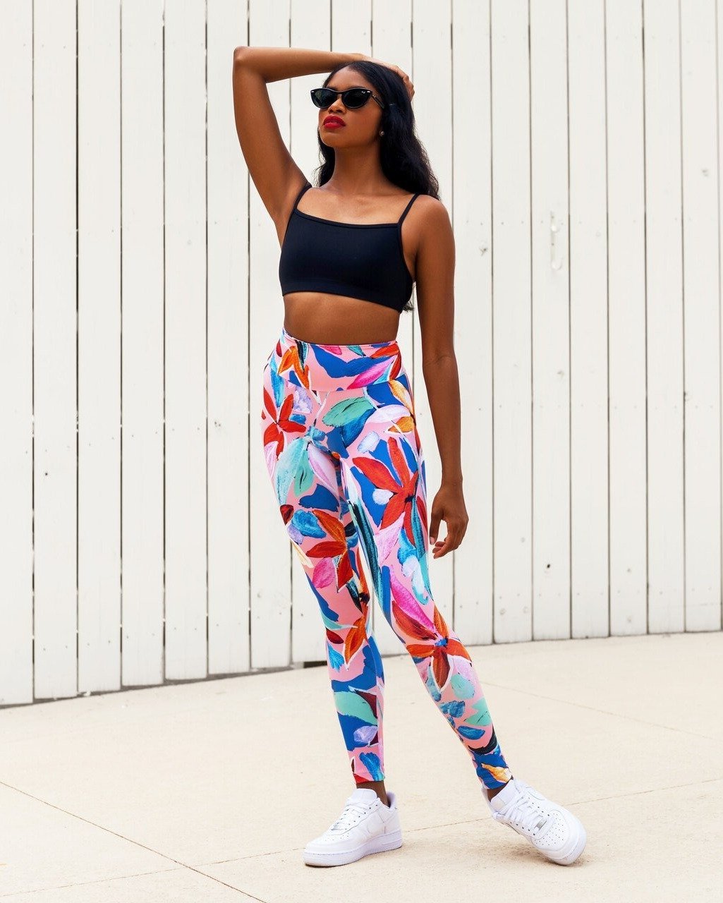 Model wearing a black athletic crop top and bright multi colored high waisted leggings yoga activewear set