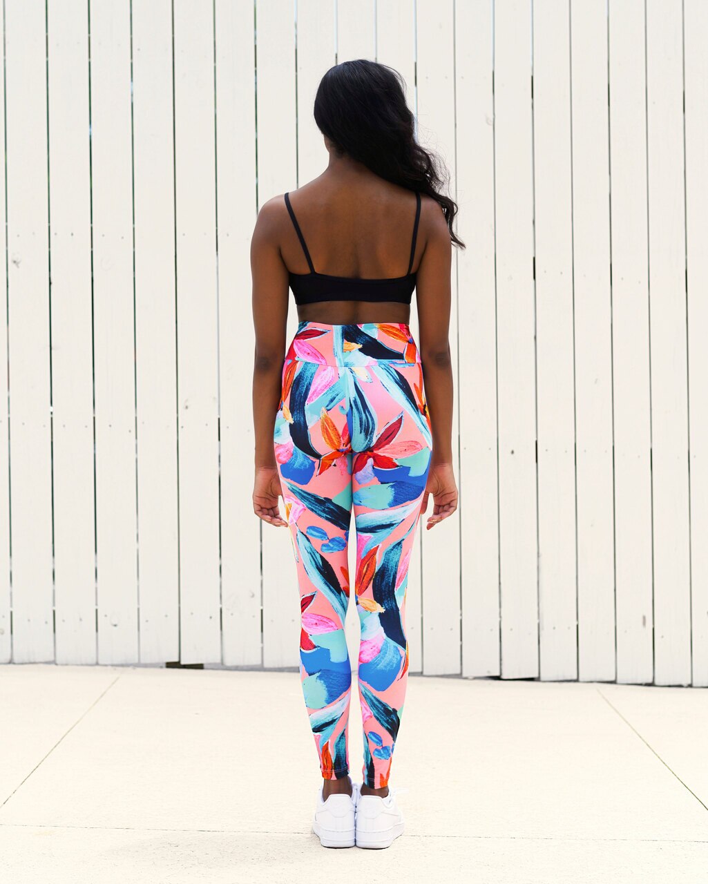 Mode wearing a black sports crop top sports bra and colorful tropical print leggings high waisted active wear yoga set