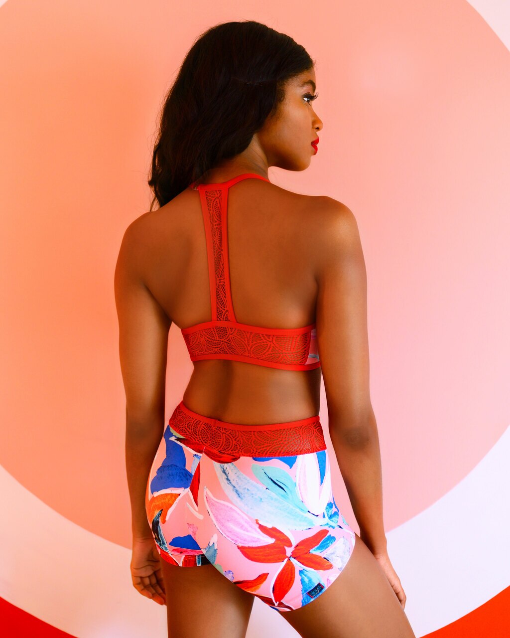 Model wearing a bright floral activewear set with red lace mesh detials yoga athletic dance wear