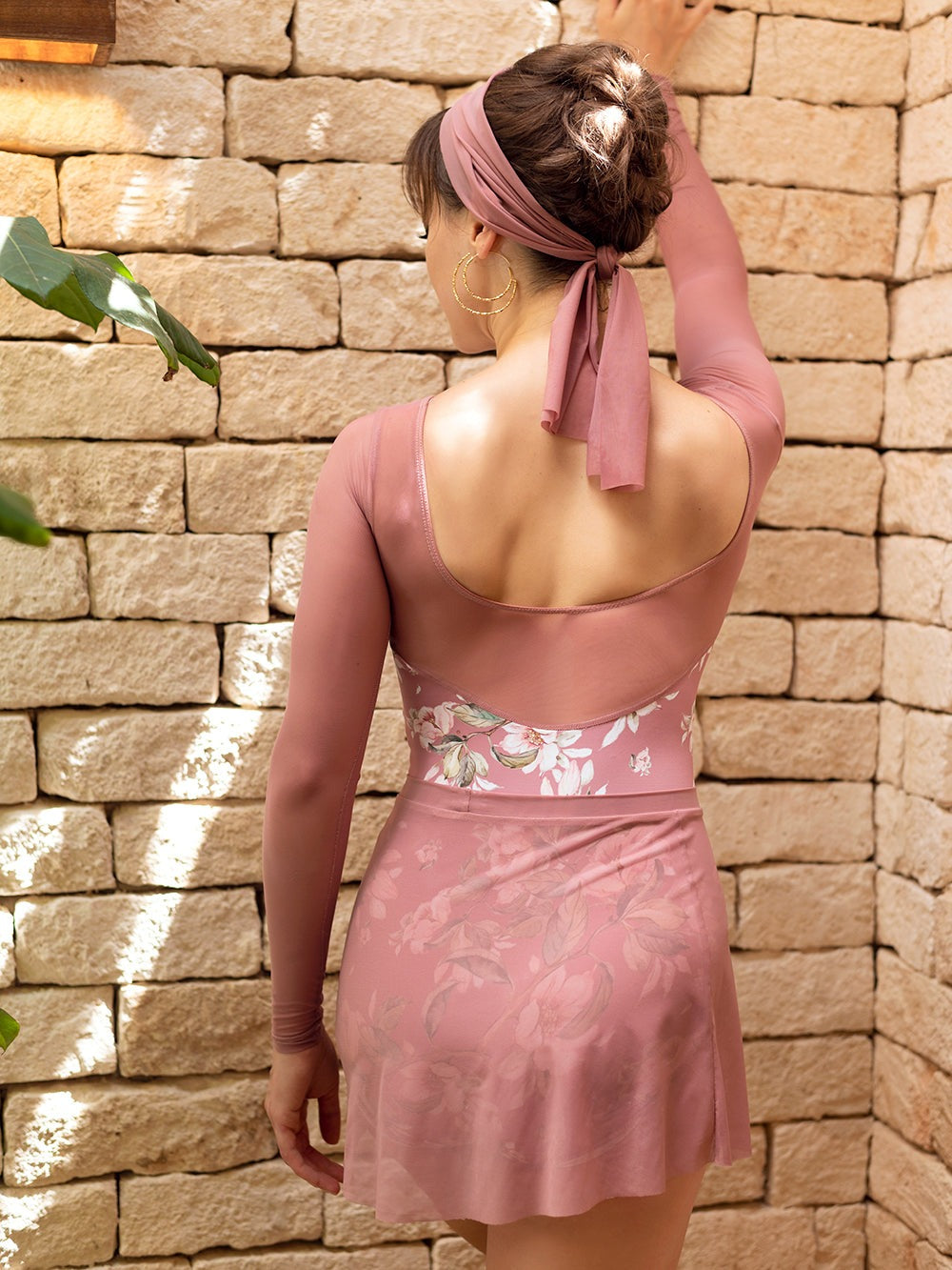 Model wearing a dark pink floral pattern leotard with mesh sleeves and a matching pink mesh skirt