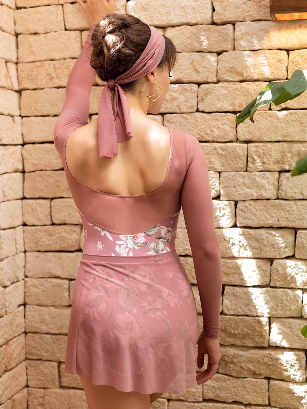 Model wearing a dark pink floral pattern leotard with mesh sleeves and a matching pink mesh skirt