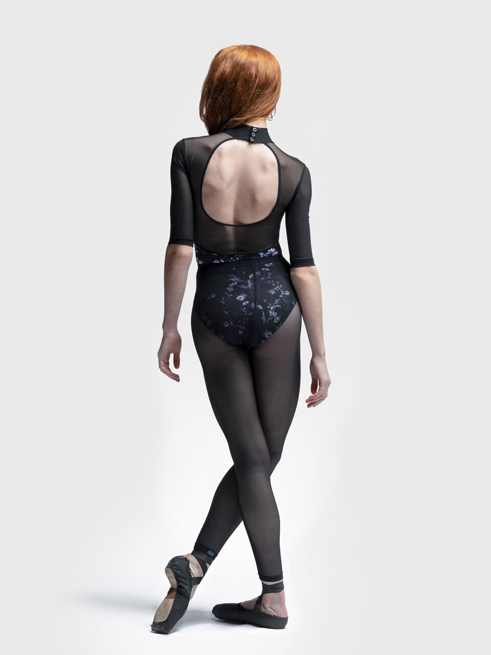 Model wearing black mesh tights over a floral leotard