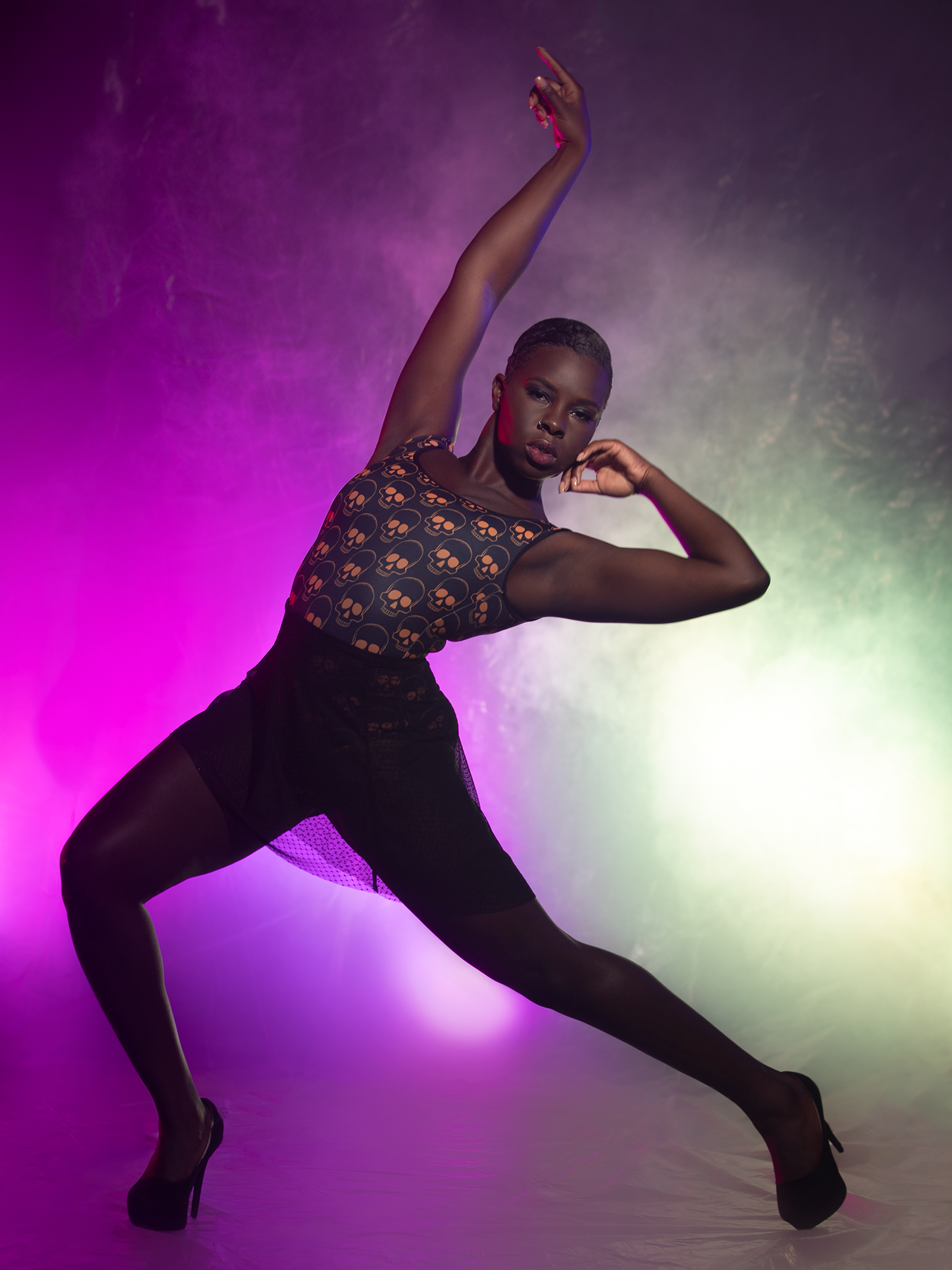 Model in Orange skull leotard and mesh striking dynamic pose.