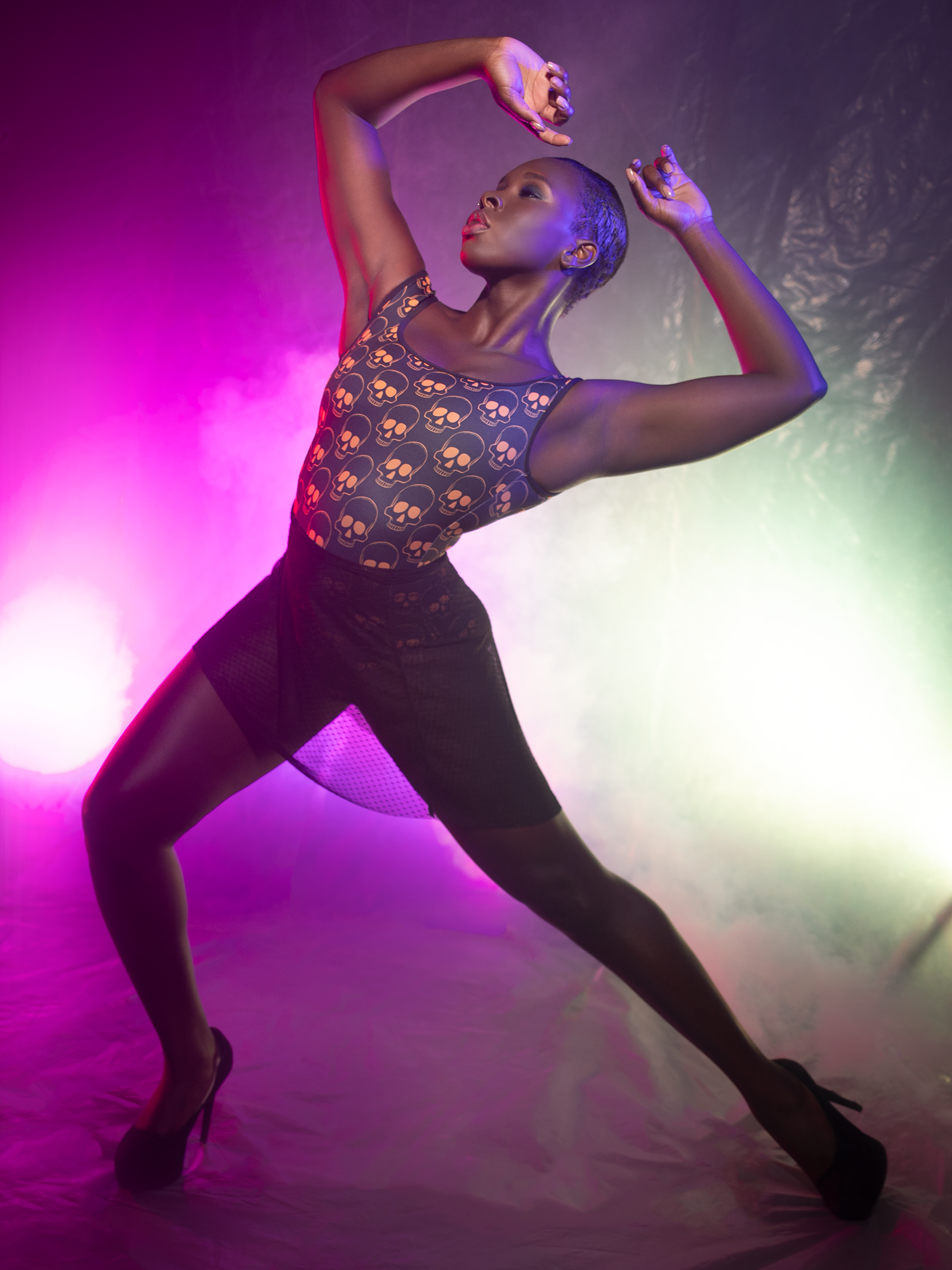 Model in dynamic pose in  leotard with orange skulls and mesh skirt