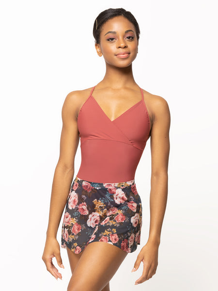 Model is wearing a dark cinnamon pink leotard with a wrap top and cami straps and a navy blue floral print mesh skirt