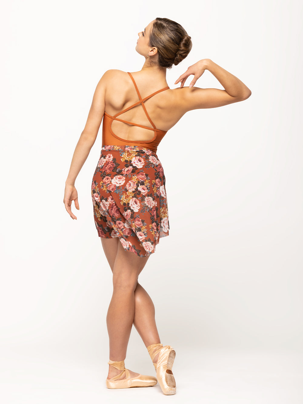 Back of model wearing shiny orange wrap halter top leotard with matching orange floral print mesh skirt
