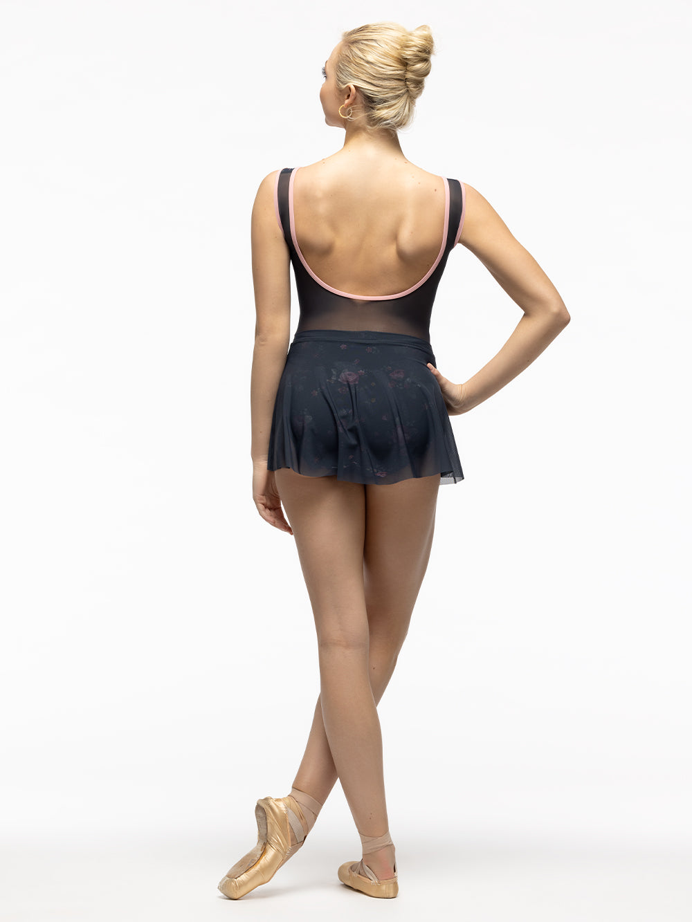 Back of model wearing navy blue and pink floral print bodysuit with zipper front, tank straps, and gray mesh scoop back. Paired with matching short gray mesh skirt.