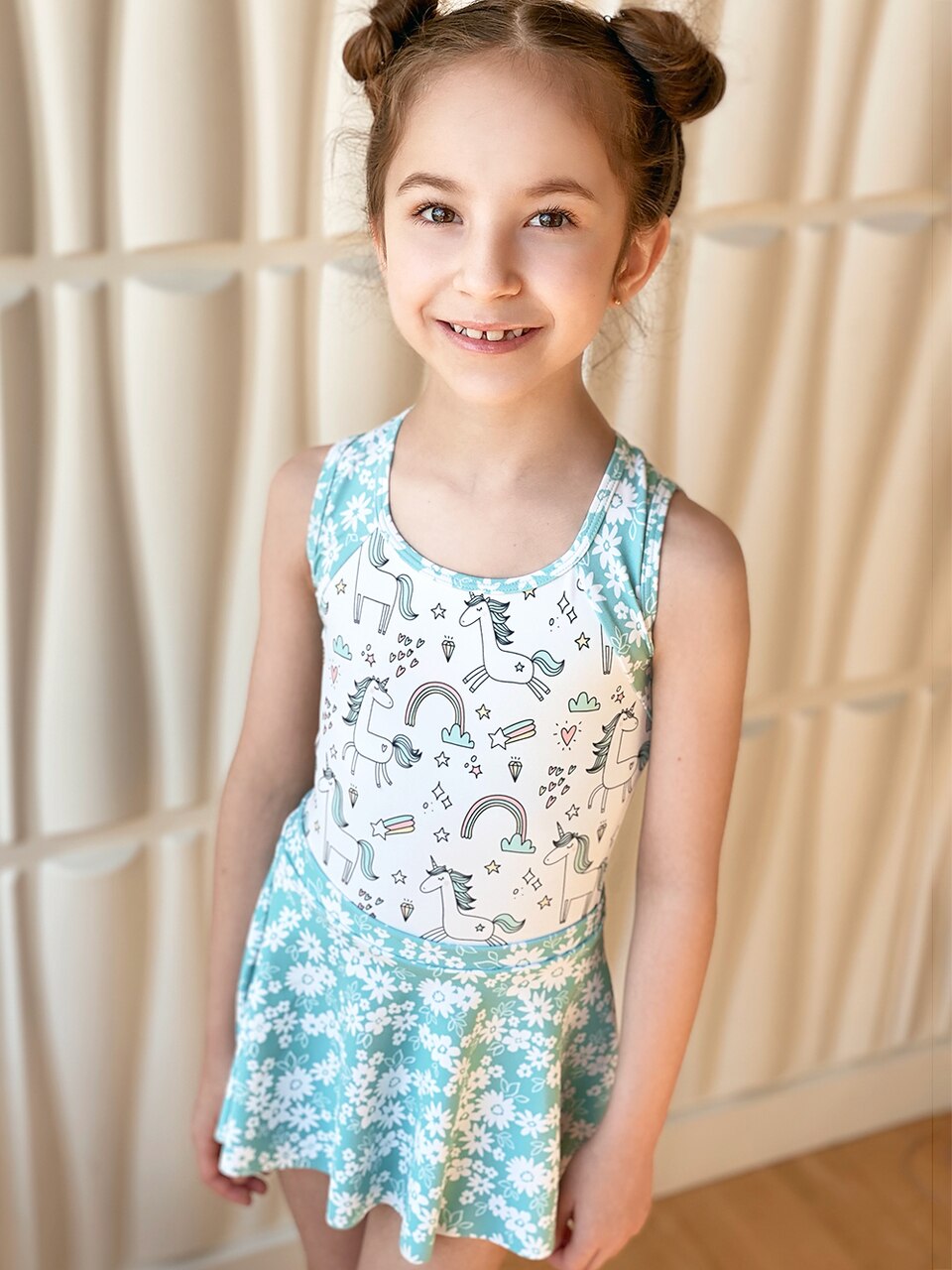 Model wearing a unicorn pattern leotard with blue floral straps and skirt