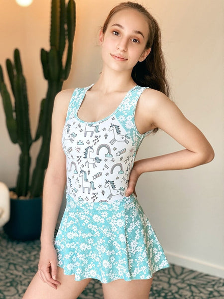 Model wearing a unicorn pattern leotard with blue floral straps and skirt