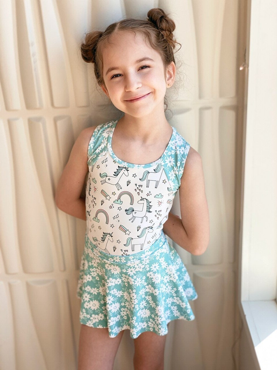 Model wearing a unicorn pattern leotard with blue floral straps and skirt