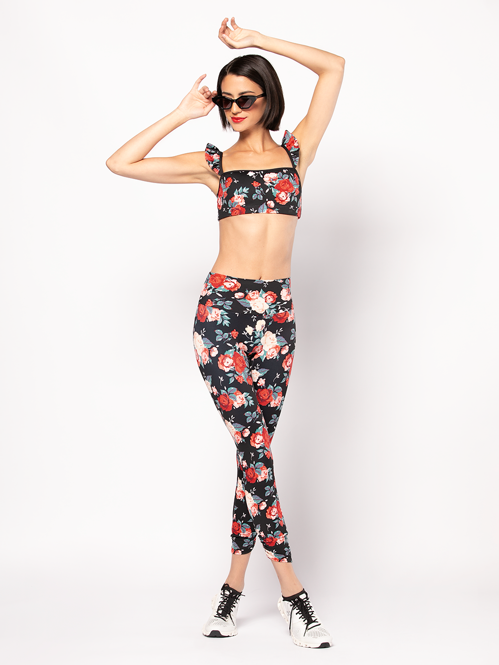 Model In Floral pattern Crop top and matching tights standing with arms raised and legs crossed