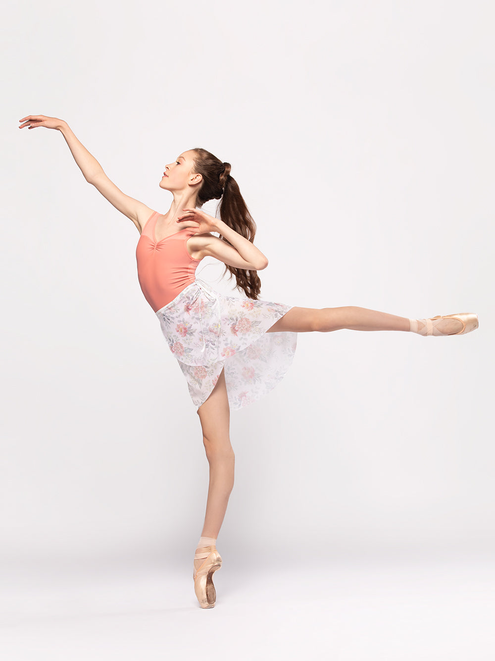 Model wearing a childrens orange leotard with a matching floral wrap skirt dance wear