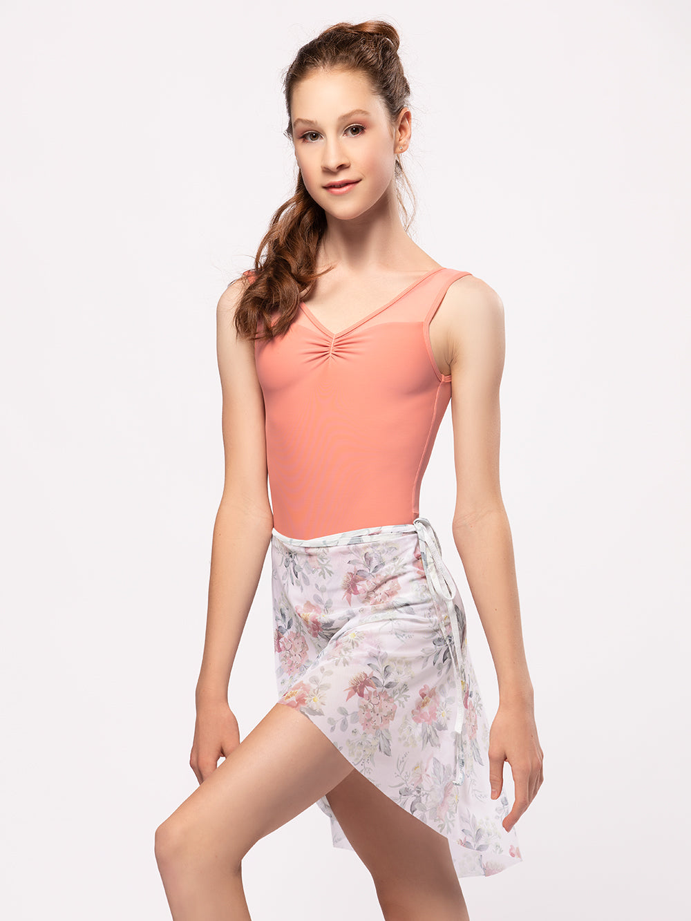 Model wearing a light peach leotard with a matching floral print long mesh wrap skirt