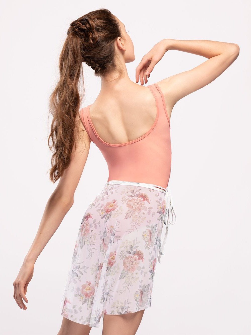 Model wearing a coral leotard body suit with a matching floral print mesh long wrap ballet skirt