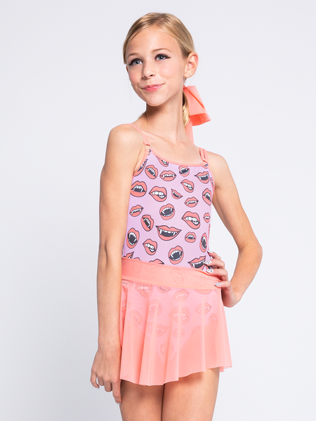 model in leotard in orchid pink with vampire fangs and coral pink skirt.
