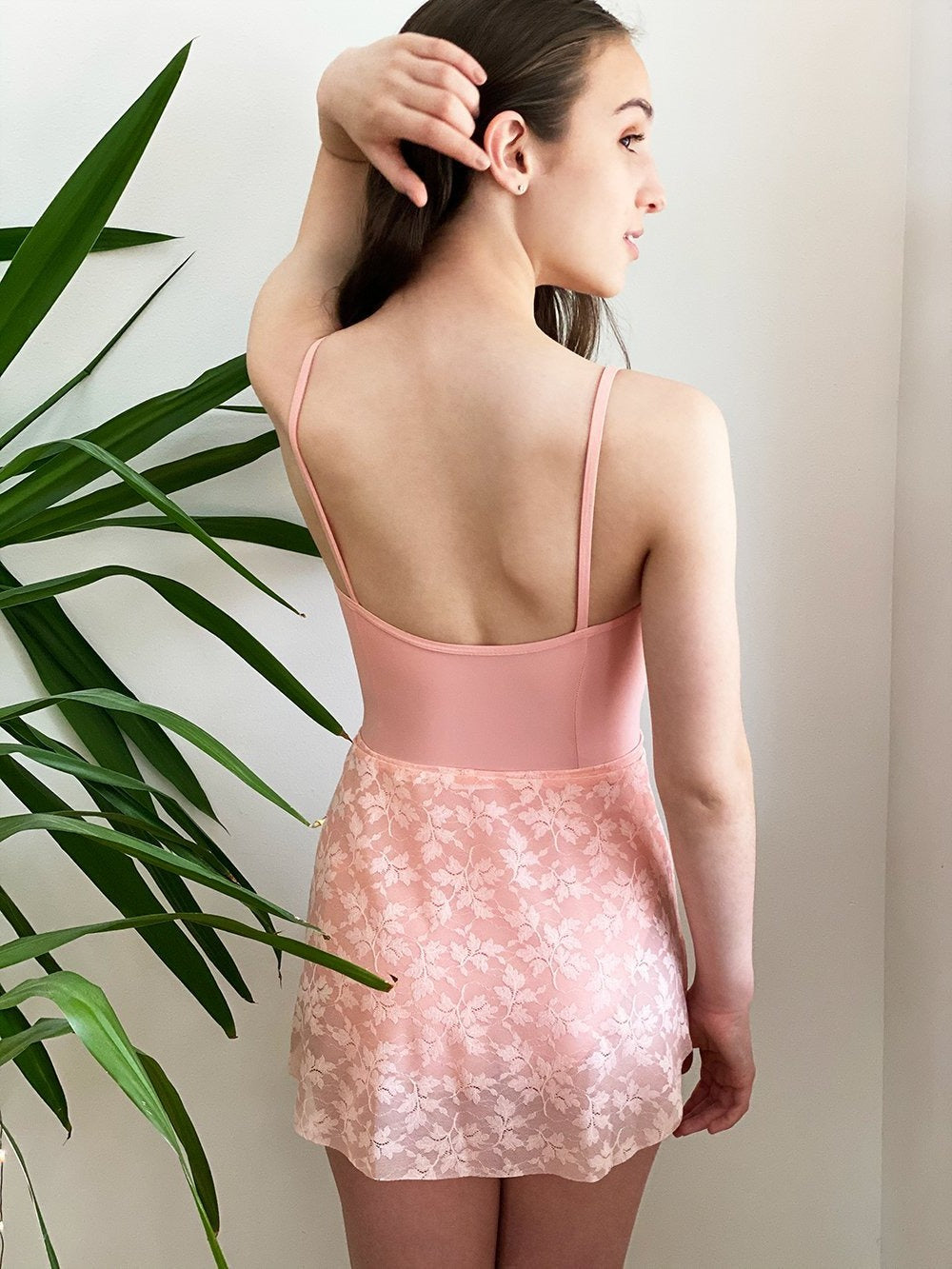 Model wearing a pink leotard with a matching pink lace mesh skirt